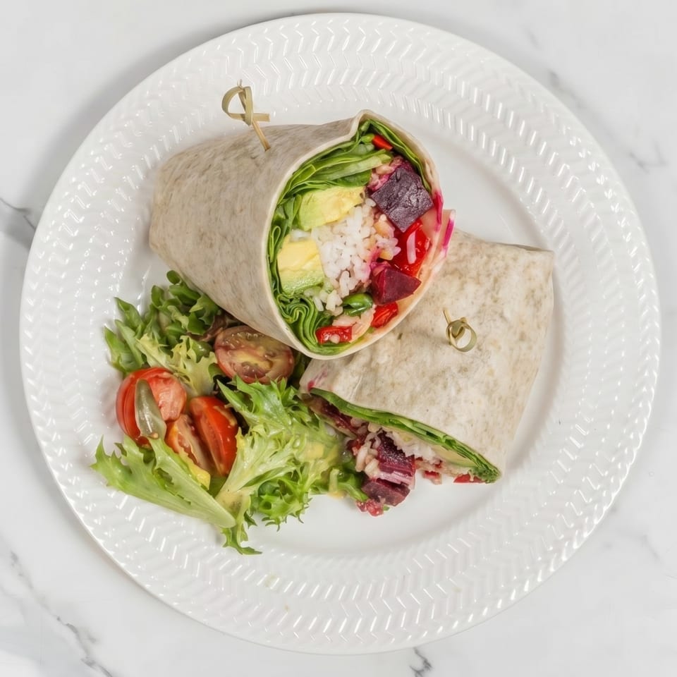 Two colorful wraps filled with rice, avocado, and beets, served with a side salad.